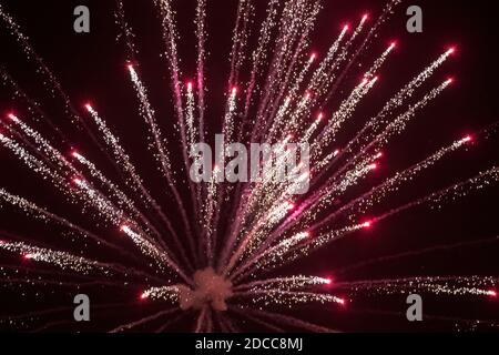 Une lumière rouge et argentée éclate alors qu'un feu d'artifice pyrotechnique explose contre le ciel nocturne dans le West Yorkshire UK Banque D'Images