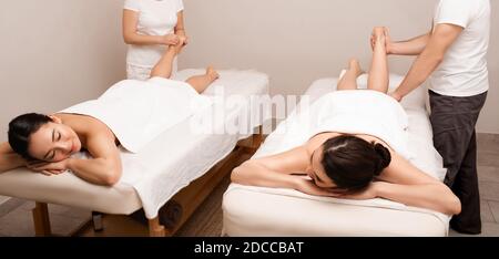 Massage des jambes et des pieds. Des femmes de race mixte heureuses lors d'un massage des jambes au spa de bien-être de traitement Banque D'Images