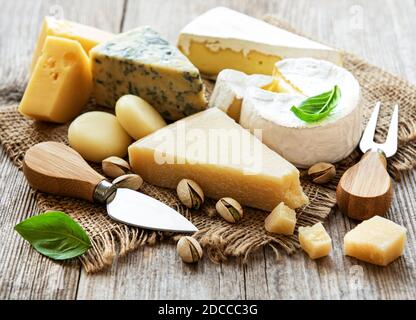 Différents types de fromage avec basilic et noix sur un ancienne table en bois Banque D'Images