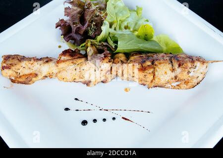 Poulet kebab sur un bâton doué avec des herbes sur une assiette. Banque D'Images