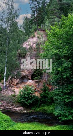 Grottes de grès à Ligatne, Lettonie. Vue sur la grotte de Lustuzis (Lustūzis) sur la rive de la rivière Ligatne. Grottes avec anciennes portes en bois. Banque D'Images