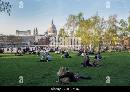 Les gens apprécient une journée chaude sur la pelouse en face du Tate Modern avec une vue sur la Tamise, la cathédrale St Paul, Londres, Royaume-Uni Banque D'Images