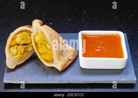 Samosa moderne servi avec une sauce chaude rouge sur un gris et un fond en marbre foncé Banque D'Images