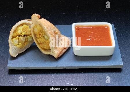 Samosa moderne servi avec une sauce chaude rouge sur un gris et un fond en marbre foncé Banque D'Images