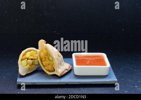 Samosa moderne servi avec une sauce chaude rouge sur un gris et un fond en marbre foncé Banque D'Images