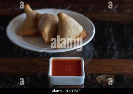 Samosas sur une assiette blanche avec sauce rouge épicée Banque D'Images