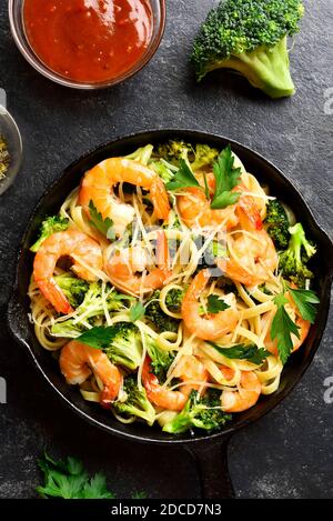 Crevettes et pâtes de brocoli dans une poêle en fonte sur fond de pierre sombre. Délicieux plat sain pour le dîner. Vue sur le dessus, plat Banque D'Images