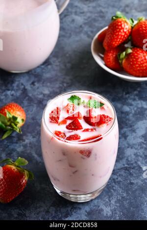 Vue rapprochée du yogourt aux fraises avec baies fraîches en verre sur fond de pierre bleue. Concept de nourriture et de boissons saines. Banque D'Images