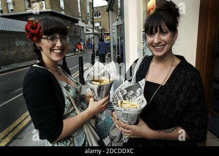 GRANDE-BRETAGNE / Angleterre / Londres / deux jeunes femmes mangeant du poisson et des frites à Bricklane près du marché de Spitalfields. Manger du poisson et des frites avec les mains. Banque D'Images