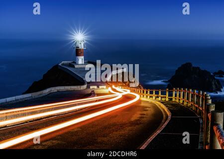 Des feux de remorque lumineux mènent au phare de Cabo Ortegal à nuit Banque D'Images