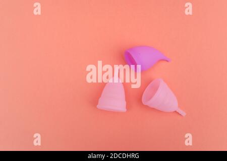 différents bouts de silicone médical menstruel période femmes tasses isolées sur fond pêche, réutilisable ecologic, zéro déchet concept. Banque D'Images
