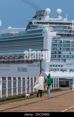 deux jeunes femmes marchant un chien avec un grand paquebot de croisière en arrière-plan dans le port de southampton Banque D'Images