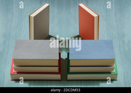 La composition symétrique et colorée de plusieurs livres l'un sur l'autre et de deux copies sur une table de bureau en bois. Banque D'Images