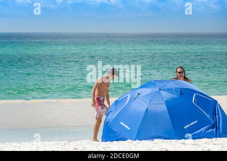 deux jeunes hommes en short de natation sortent de la mer Vers leur soleil ou parasol sur la plage à Biloxi Mississippi États-Unis Banque D'Images