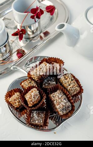 Chocolat fait à la main recouvert de cacao et de chapelure de noix. Encore la vie avec des bonbons et des appareils de thé. Banque D'Images