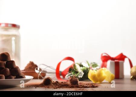 Truffes au chocolat en préparation sur une table de cuisine pour les vacances de Noël avec des ingrédients et cadeau avec fond blanc isolé. Vue avant. Banque D'Images