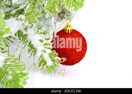 Boule de Noël rouge brillant accrochée à une branche de sapin dépoli dans la neige. Copier l'espace Banque D'Images