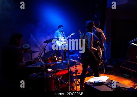 Le groupe de rock de Mexico City joue entre le brouillard artificiel et le batteur à lumière bleue, le bassiste et une paire de guitaristes Banque D'Images