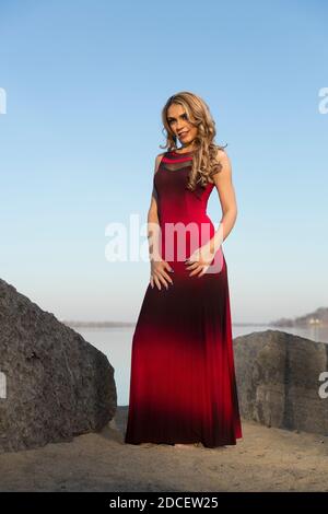 Portrait d'une femme à la plage portant un long rouge et robe noire Banque D'Images