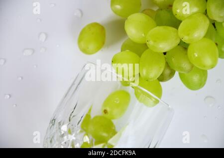 raisins blancs dans un verre à vin. Vin blanc dans un verre de raisin d'automne, fond blanc, mise au point sélective. Banque D'Images