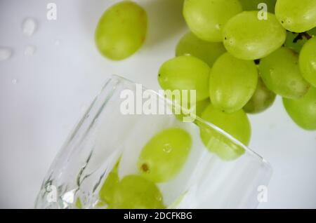 raisins blancs dans un verre à vin. Vin blanc dans un verre de raisin d'automne, fond blanc, mise au point sélective. Banque D'Images