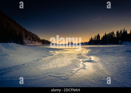 Panorama d'hiver du lac Calaita au crépuscule. Lac gelé, forêts de sapins et prairies enneigées. Vallée de Lozen, Trentin-Haut-Adige Banque D'Images