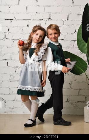 Portrait de deux élèves de l'école élémentaire en uniforme avec Apple et tablette. Prêt pour la première journée d'école. Journée de la connaissance - 1er septembre. Banque D'Images