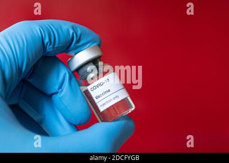Gros plan de la main du médecin portant des gants de protection bue portant une bouteille complète de vaccin contre le coronavirus Covid-19 contre la pandémie de covid. Intenti Banque D'Images