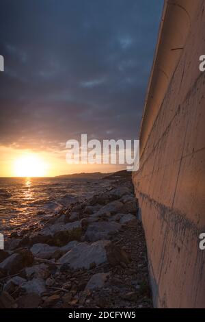 Mur en béton le long de la côte, avec l'autoroute N340 au-dessus, coucher de soleil, El Faro de Calaburras, Andalousie, Espagne. Banque D'Images