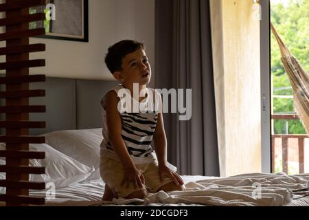 Un enfant détendu regardant la télévision dans la chambre d'hôtel avec sa mère couché dans un hamac en arrière-plan. Banque D'Images