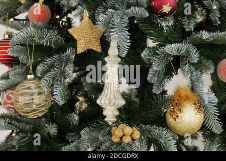 Décorations de Noël sur un arbre dans la maison. Des décorations de Noël rouges et dorées sont accrochées à l'arbre. Banque D'Images