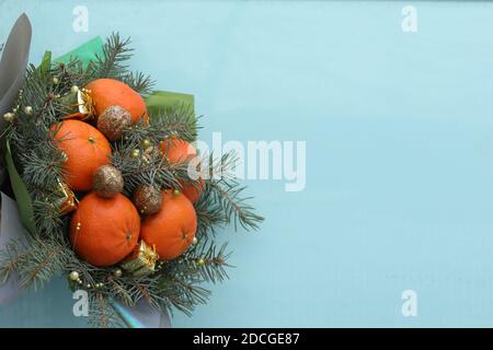 Bouquet de Noël de branches de sapin, mandarines et petites boîtes-cadeaux sur fond bleu. Nouvelle année Banque D'Images