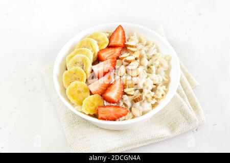 Porridge de flocons d'avoine maison avec fraise, banane et noix dans un bol sur fond de pierre Banque D'Images