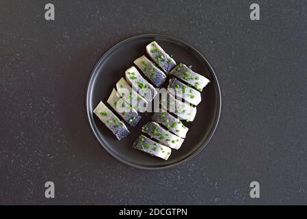 Hareng salé sur plaque sur fond de pierre sombre. Vue de dessus, plan d'appartement Banque D'Images