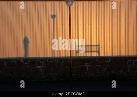 Ombres du banc, du lampost et du photographe sur un mur ondulé.Une image de conception .Espace pour le texte autour et dans la monnaie Banque D'Images