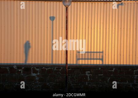 Ombres du banc, du lampost et du photographe sur un mur ondulé.Une image de conception .Espace pour le texte autour et dans la monnaie Banque D'Images