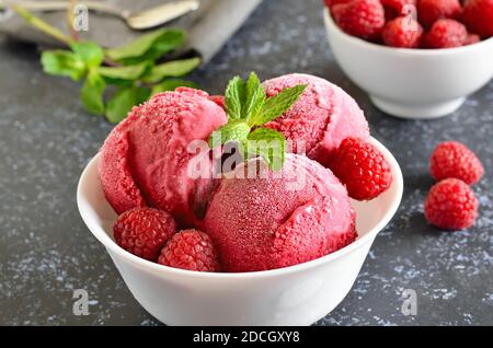 Cuillère à crème glacée à la framboise dans un bol, vue rapprochée. Dessert d'été froid Banque D'Images