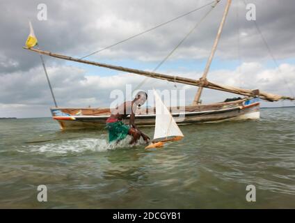 Jeune garçon jouant avec le modèle de dhow le long de la mer, comté de Lamu, Lamu, Kenya Banque D'Images