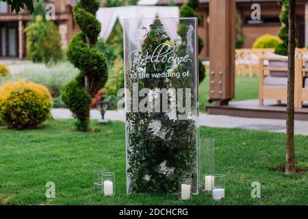 Bienvenue au mariage de l'affiche en verre stand décoré de fleurs et de bougies sur des verres sur l'herbe sur la fête de mariage Banque D'Images