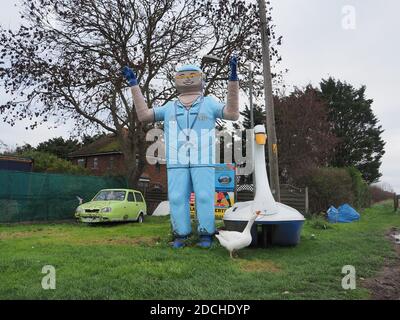 Leysdown, Kent, Royaume-Uni. 21 novembre 2020. Une oie est devenue le meilleur ami avec un vieux bateau d'amusement 'wan bateau', qui est maintenant situé à l'extérieur de Bay View Garden Center près de Leysdown dans le Kent. L'oie est régulièrement vue assis avec le cygne en plastique beaucoup plus grand. Le 'Leysdown Giant' est également à proximité et a été décoré pour soutenir le NHS. Crédit : James Bell/Alay Live News Banque D'Images