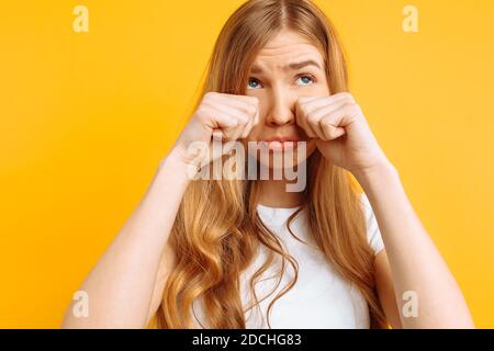 belle fille bouleversée, femme pleurant sur fond jaune, mauvaise humeur Banque D'Images