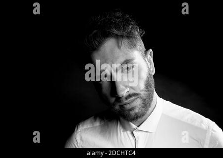 Un homme sur un fond sombre. Avec des sourcils en sillons.avec des pensées d'un avenir difficile. Banque D'Images