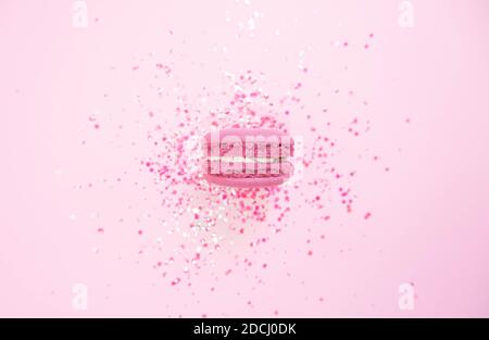 Macaron sur fond rose pastel scintillant. Plat Banque D'Images