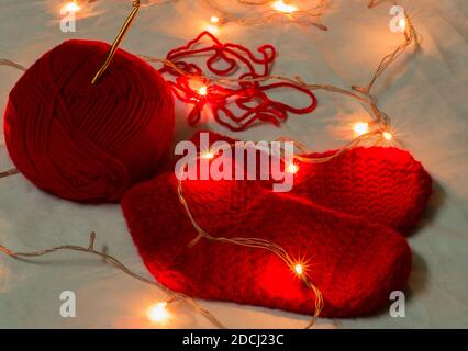 Chaussettes de noël en laine de couleur rouge faites à la main, aiguille en crochet et boule en laine illuminée de lumières de noël miniatures. Arrière-plan de l'espace de copie. Fa d'hiver Banque D'Images