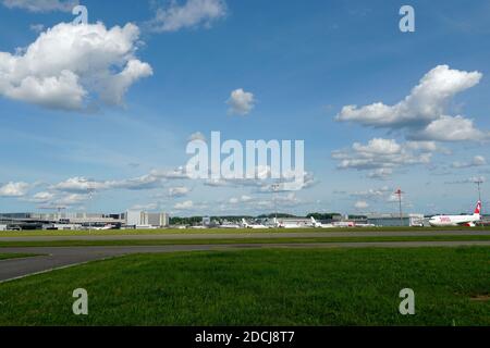 Piste d'atterrissage à l'aéroport de Zurich avec des bâtiments et des avions toujours debout en arrière-plan et dans l'espace de copie. Ciel avec des cumulus nuages souligne l'impression. Banque D'Images