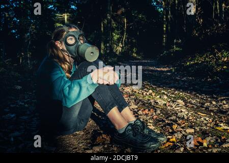 Fille avec masque à gaz dans la forêt au coucher du soleil Banque D'Images