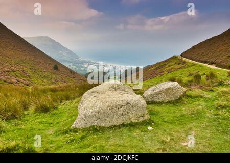 Vue en hauteur avec Penmaenmawr et la mer d'Irlande au loin et grands rochers au premier plan. Pays de Galles du Nord, Royaume-Uni. Banque D'Images