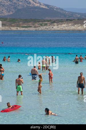 Les gens se rassemblent pour s'amuser, jouer et se détendre dans l'eau à la mer méditerranée en Sardaigne, Stintino, Italie Banque D'Images