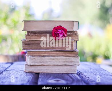 Carte vintage avec pile de vieux livres et rose rouge fleurs à l'extérieur