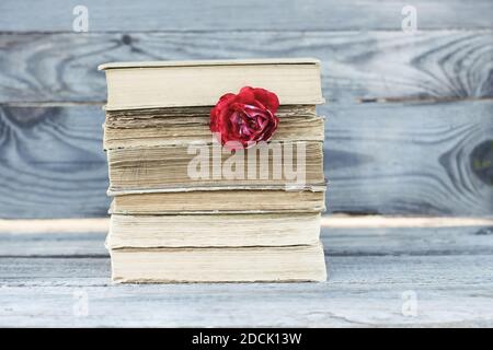 Carte vintage avec pile de vieux livres et rose rouge fleurs à l'extérieur